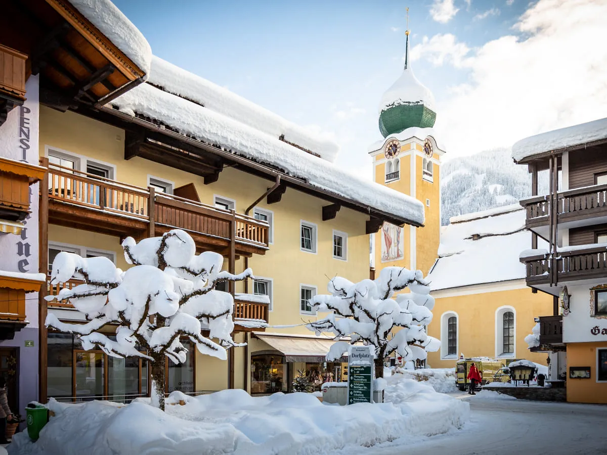 Winterlandschaft mit schneebedeckten Bäumen und einem Kirchturm im Hintergrund